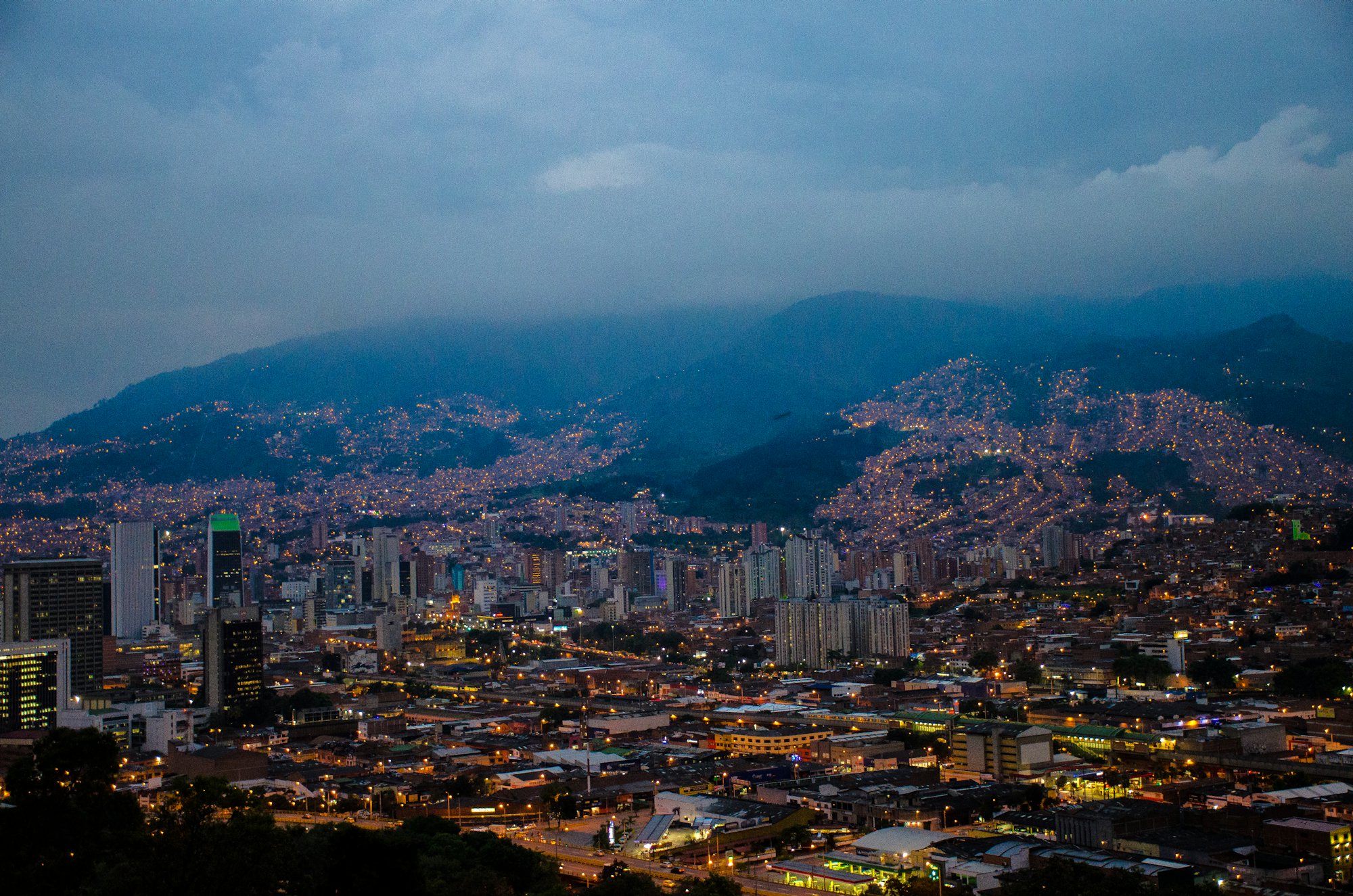 Medellín al atardecer, con las luces de los barrios subiendo por las laderas